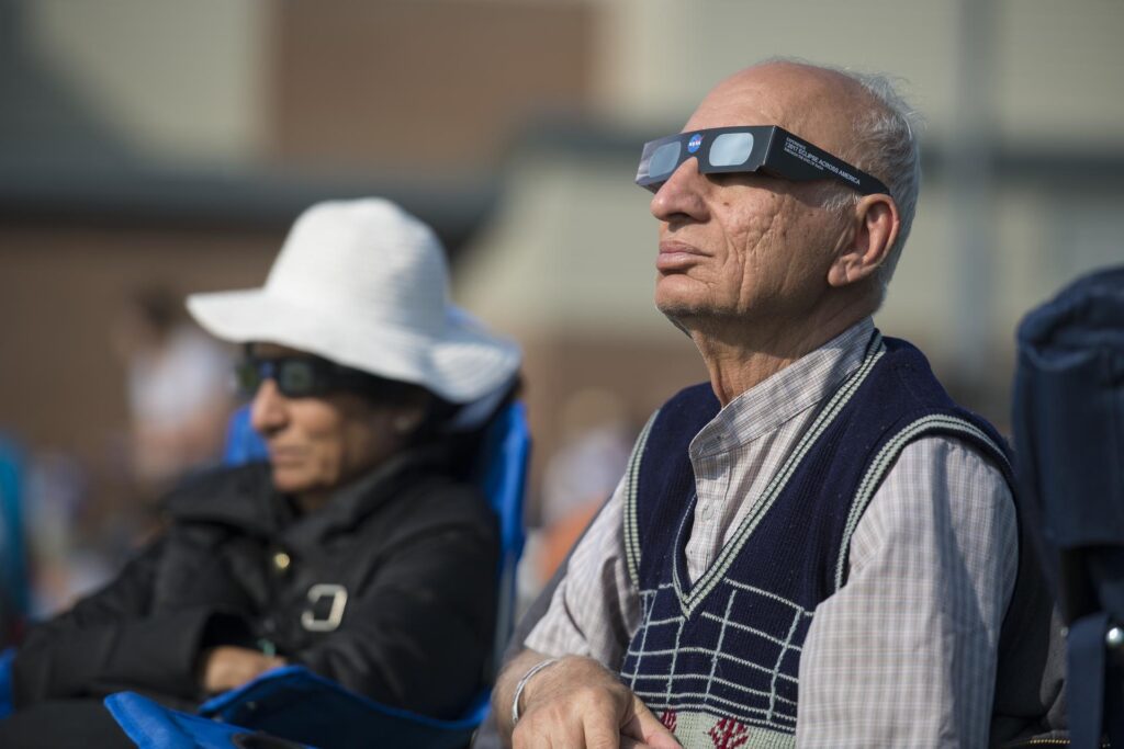 People are seen as they watch a total solar eclipse through protective glasses in Madras, Oregon on Monday, Aug. 21.
Photo Credit: (NASA/Aubrey Gemignani)